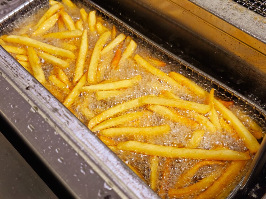 Pommes frites i bubblande olja i fritös.