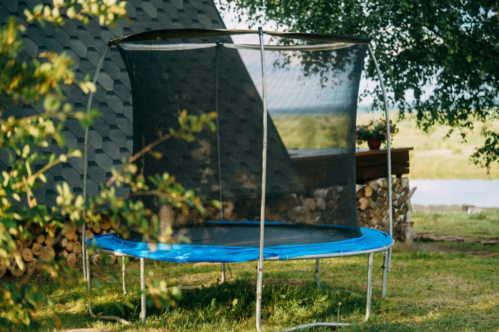 Oanvänd studsmatta i trädgården en solig dag.