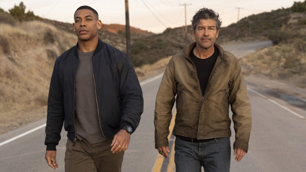 Aaron Pierre och Kyle Chandler går längs en bilväg i en scen från serien Lanterns.